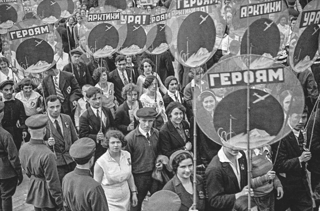 Молодёжь на Красной площади несёт круглые плакаты «Героям Арктики» с самолётом, 19 июня 1934 года