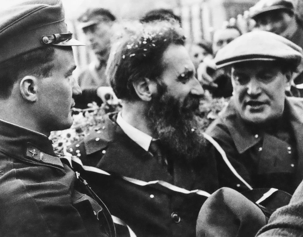 Николай Каманин в фуражке, Отто Шмидт с конфетти в бороде и Валериан Куйбышев в кепке на встрече челюскинцев, июнь 1934 года