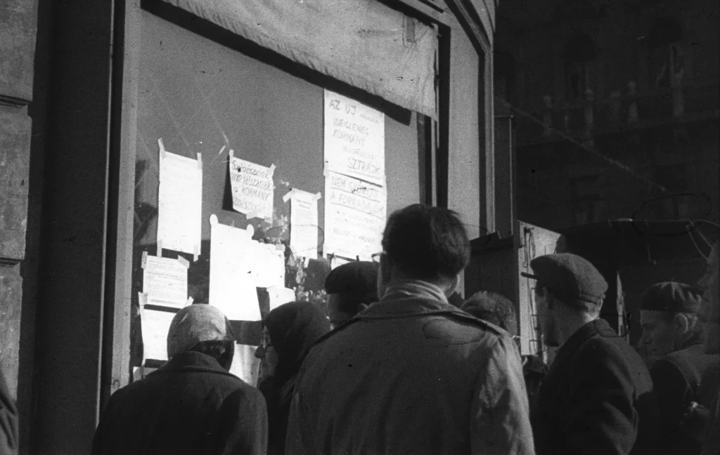 Прохожие читают объявления и листовки, наклеенные на витрину магазина в Будапеште, 1956 год