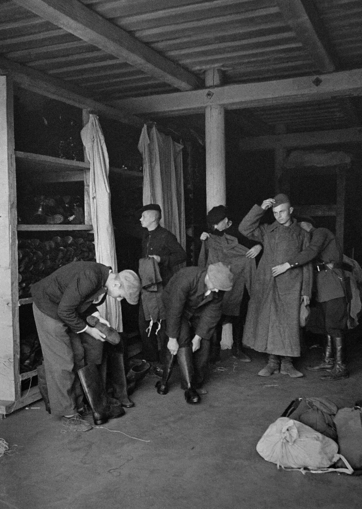 Новобранцы примеряют сапоги и шинели на вещевом складе, 24 июня 1941 года