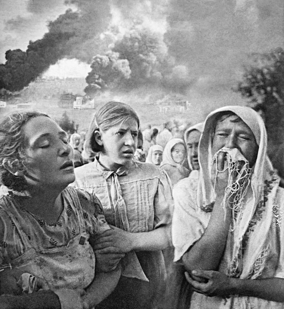 Плачущие женщины и девушка в Киеве на фоне горящих после бомбёжки домов, 23 июня 1941 года