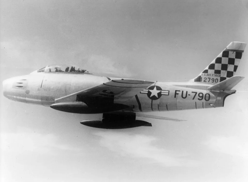 Реактивный истребитель F-86E «Сейбр» с шахматной окраской киля в полёте над Кореей