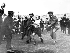 Финиш Дорандо Пьетри на марафоне Олимпиады 1908 года в Лондоне: его ведут Джек Эндрю и доктор Майкл Балджер