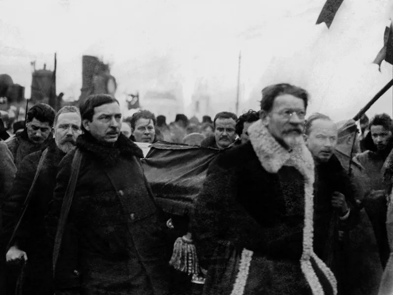 Михаил Калинин в шубе с меховым воротником и другие члены руководства несут гроб Ленина на руках через толпу, январь 1924 года