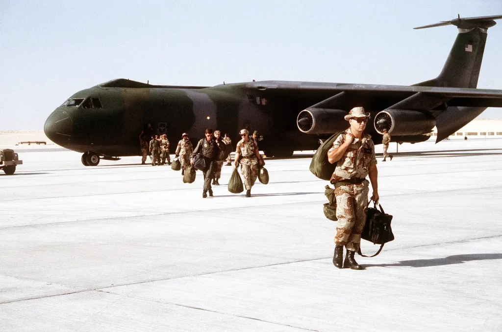 Американские военные с вещмешками выходят из транспортного самолёта C-141B на аэродроме в Саудовской Аравии