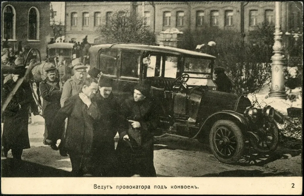 Конвой с винтовками ведёт арестованного к автомобилю