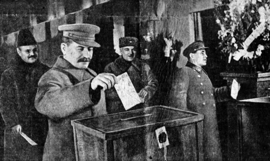 Сталин опускает бюллетень на выборах в Верховный Совет СССР 12 декабря 1937 года, рядом Молотов, Ворошилов и Ежов