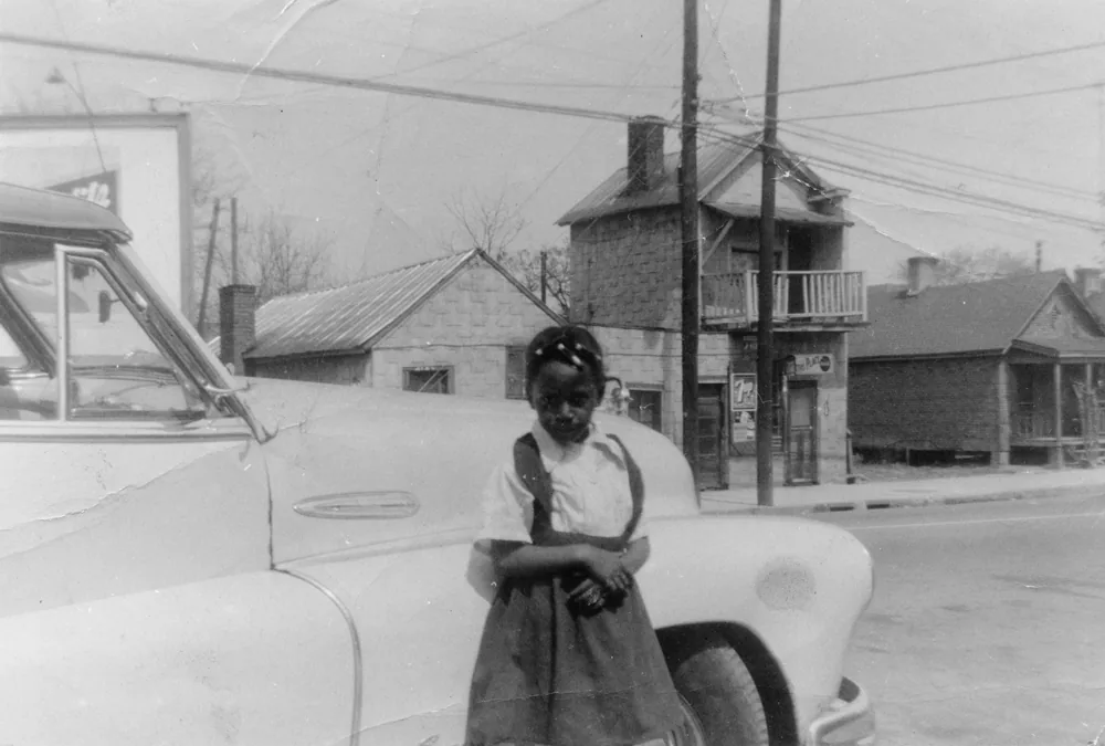 Девочка в юбке на лямках стоит у светлого кабриолета Pontiac 1953 года на улице Роли, Северная Каролина, 1957 г.