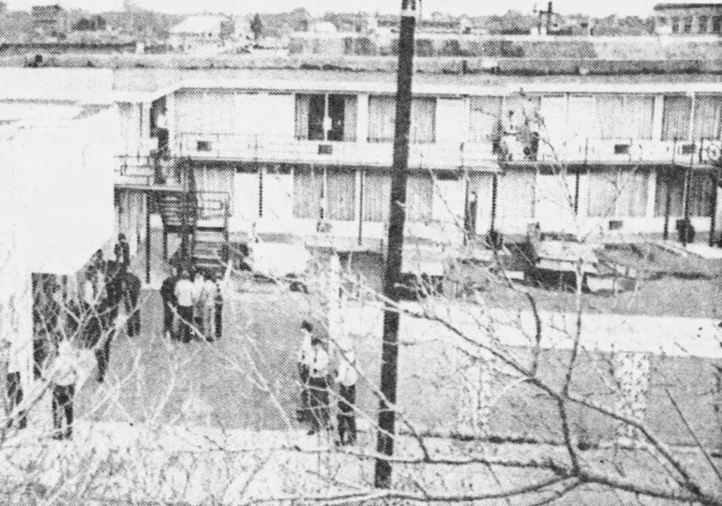 Полицейские во дворе мотеля «Лоррейн» вечером после убийства Кинга, вид из-за деревьев, Мемфис, 4 апреля 1968 года